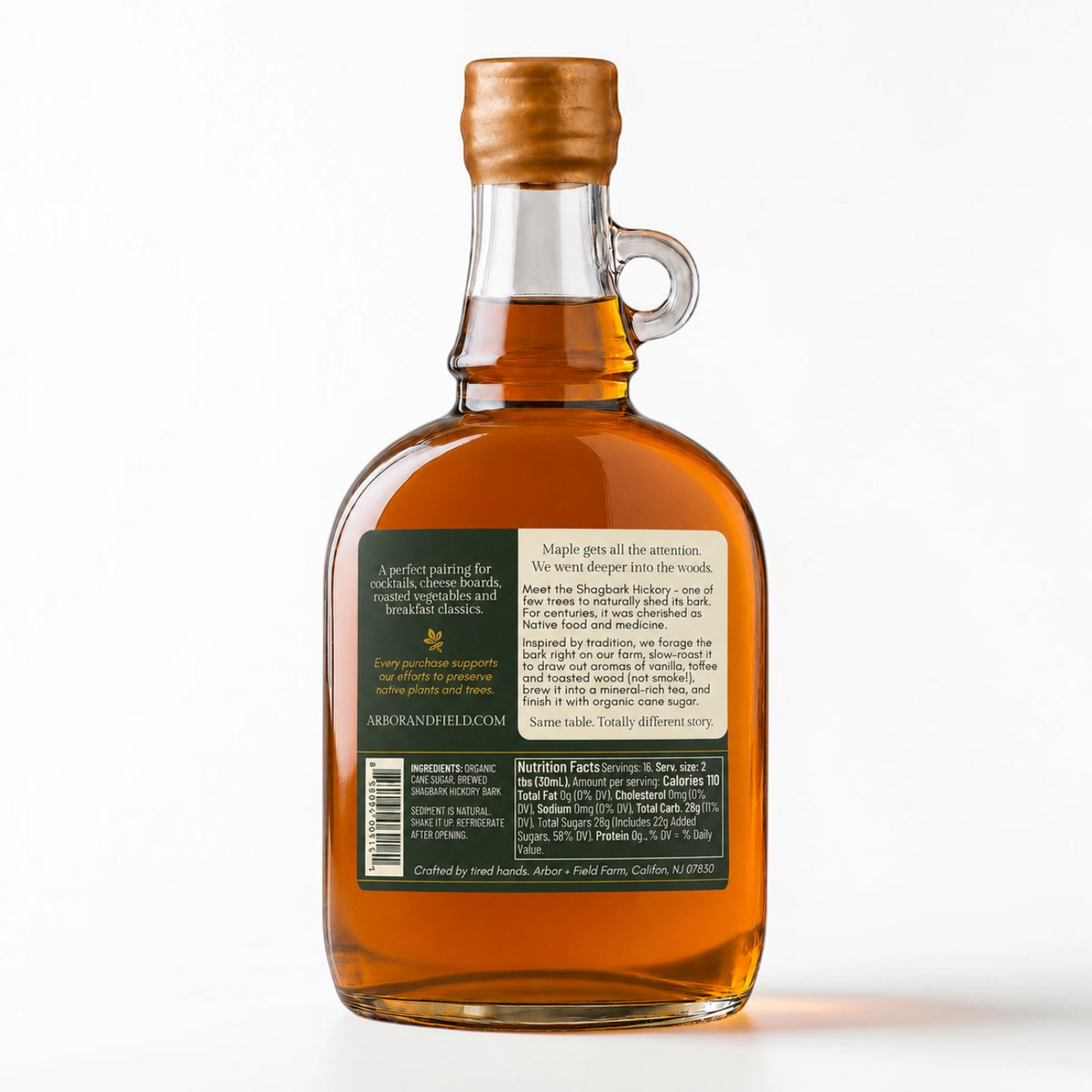 Shagbark Hickory Syrup 16 oz growler bottle with a gold wax dipped cap, green and cream Arbor and Field Label on the back with pairing suggestions and a description of how the product is crafted. Clean white background, premium look and feel. 
