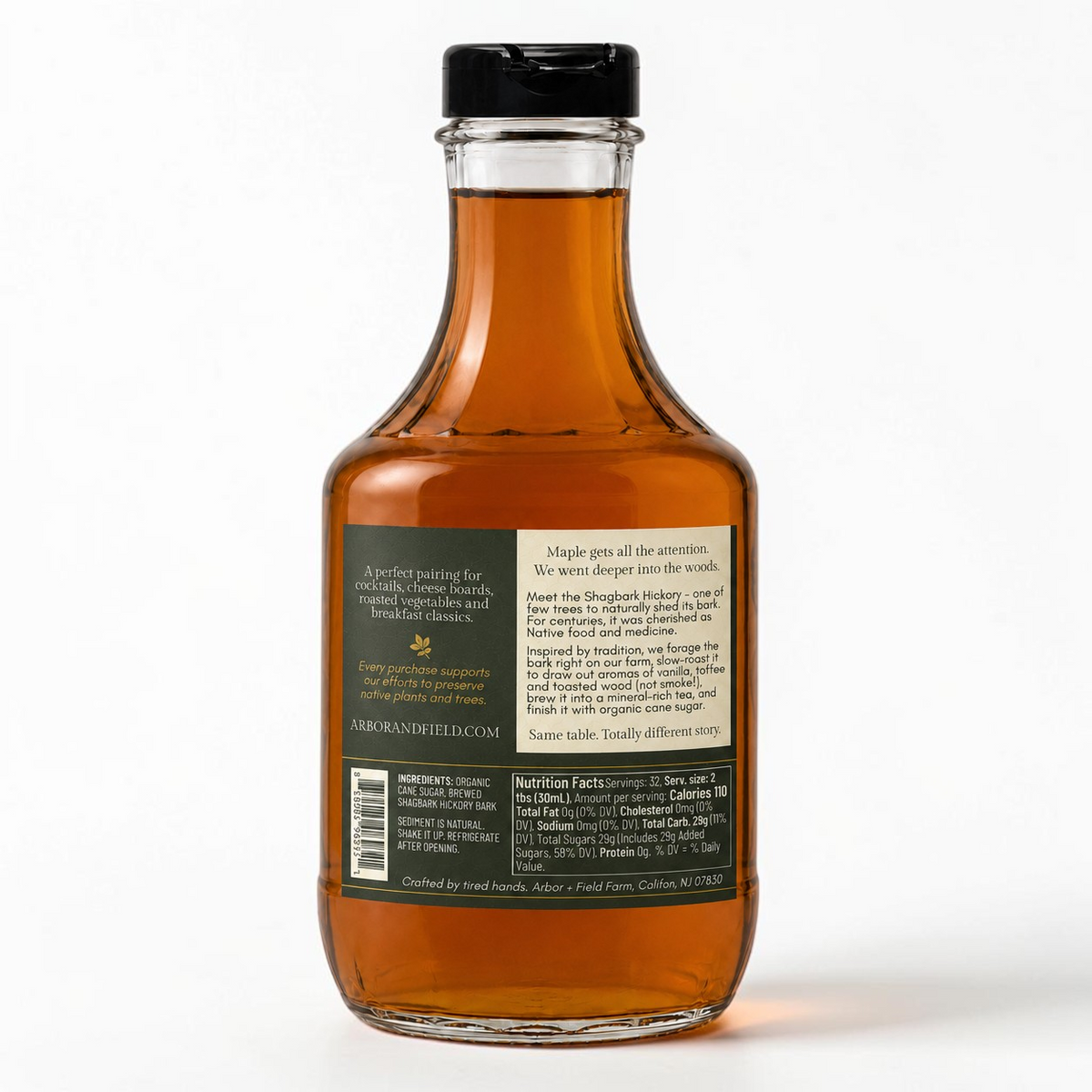 Shagbark Hickory Syrup 32 oz decanter bottle with a gold wax dipped cap, green and cream Arbor and Field Label on the back with pairing suggestions and a description of how the product is crafted. Clean white background, premium look and feel. 