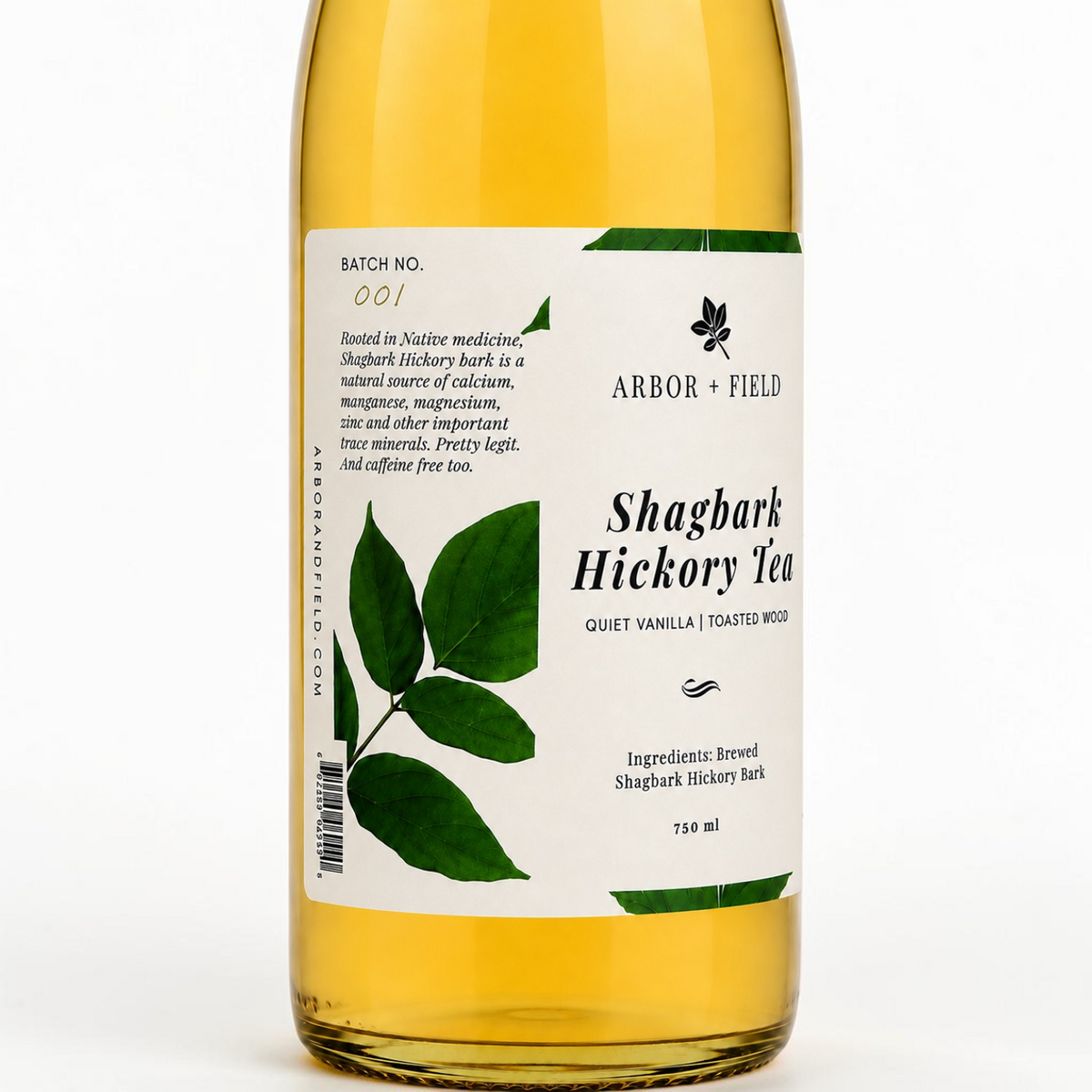 Close up of bottle of Arbor and Field shagbark hickory tea with a green and white label and handwritten batch number on the left side. Modern clear glass wine bottle with amber colored tea inside. Clean white background, premium look and feel. 